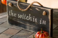 a wooden sign paired with some faux pumpkins for chic and stylish Halloween decor