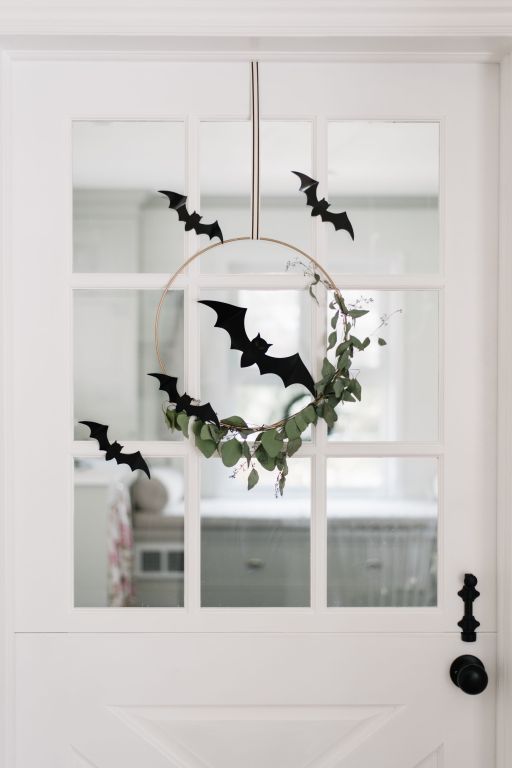 minimalist Halloween door decor with a wreath with greenery, black paper bats is a lovely idea for fall celebrating