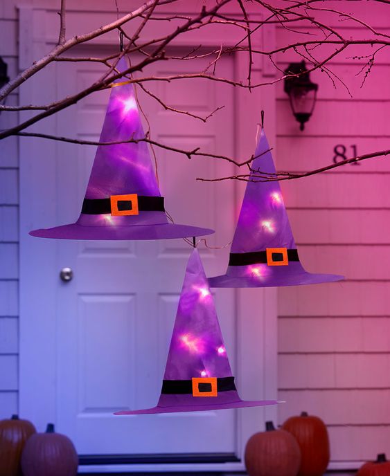 outdoor Halloween decor with purple paper witches' hats with lights hanging on branches is creative and easy to DIY