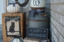 rustic Halloween styling with hay, white pumpkins with black bows, a wooden box with a cat and a vine wreath