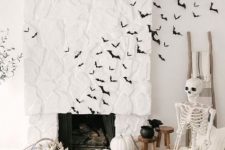 stacked white pumpkins, a skeleton on  a chair, black bats and blackbirds are amazing to style your space for Halloween