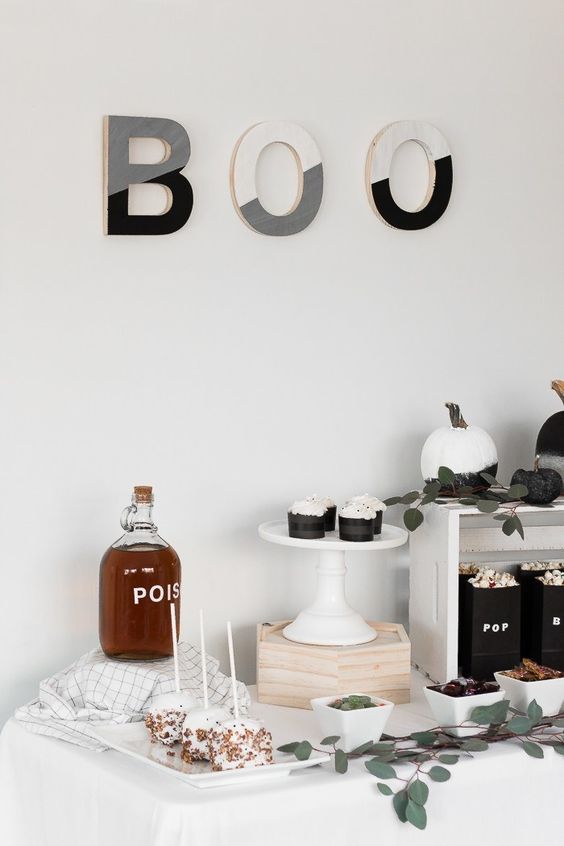 stylish Halloween decor with color block letters, black and white pumpkins, greenery and black packs of popcorn is awesome