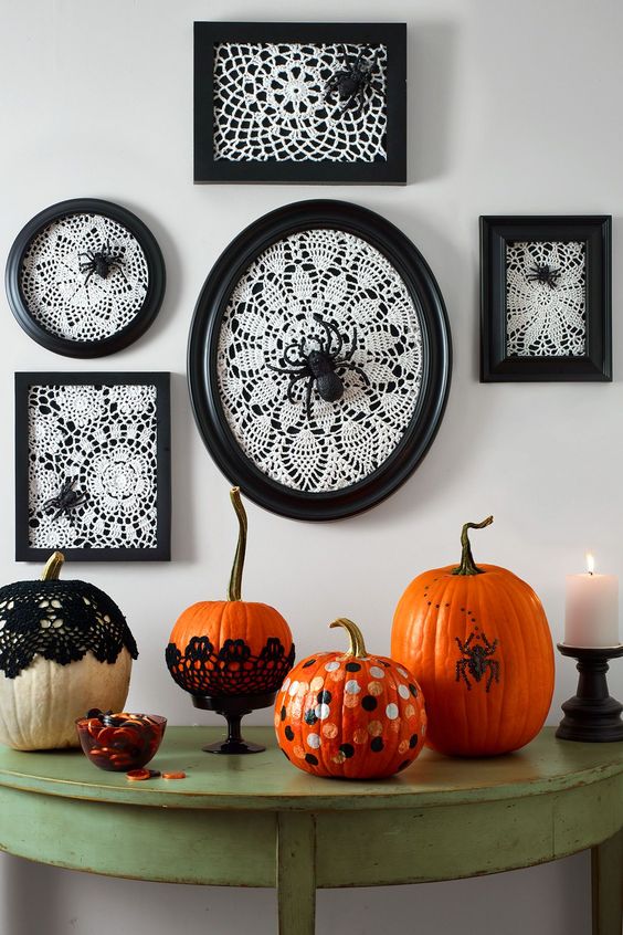 vintage Halloween console styling, with white doilies in black frames, spiders, bold pumpkins with polka dots and in doilies plus a candle