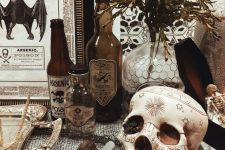 vintage Halloween decor with a patterned skull, poison bottles, greenery, vintage signs and artworks is easy to recreate yourself