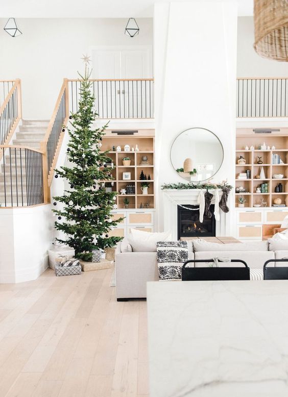 a Christmas tree decorated with white and black ornaments and lights plus matching stockings on the mantel