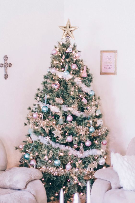 a Christmas tree decorated with pastel green and pink ornaments, stars, lights and fluffy garlands plus a star topper