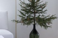 a Christmas tree in a dark green bottle with white candles and a star is a stylish minimalist idea