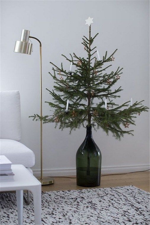 a Christmas tree in a dark green bottle with white candles and a star is a stylish minimalist idea