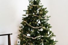 a Nordic minimalist Christmas tree decorated with white ornaments and wooden bead garlands plus lights