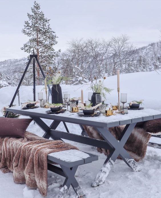 a Scandinavian Christmas tablescape with black porcelain, vases with dried blooms and grasses, gold mugs and tall and thin candles