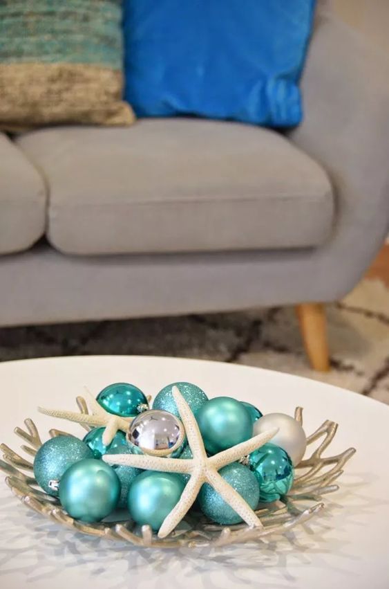 a beach Christmas centerpiece of a silver coral bowl, turquoise and silver ornaments and star fish is a lovely idea