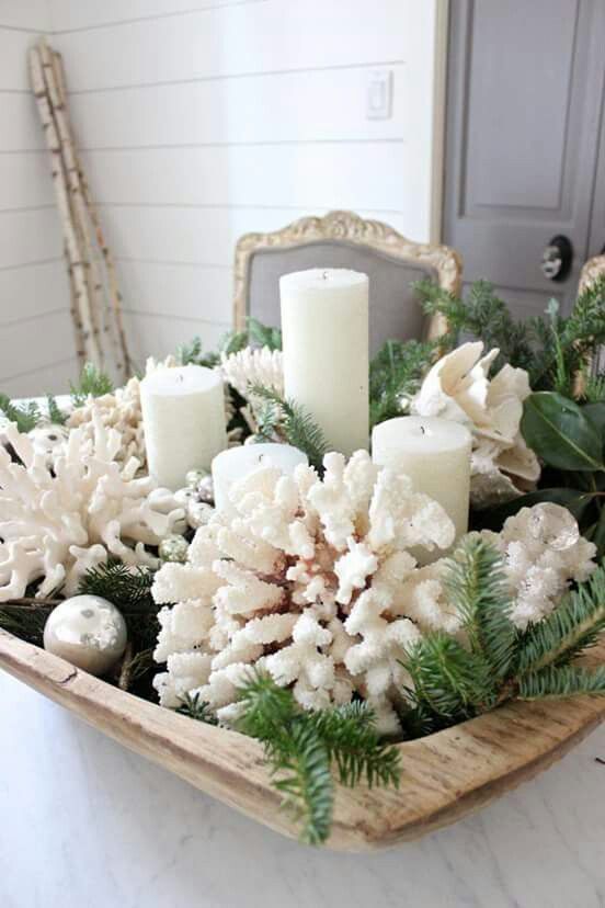 a beach Christmas centerpiece of a wooden bowl, with evergreens, corals, pillar candles, silver and pearl-colored ornaments is amazing