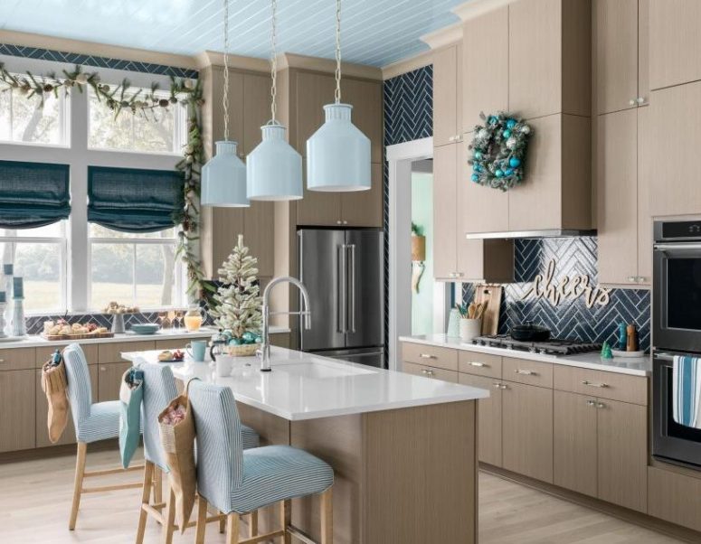 a beach Christmas kitchen with a tabletop Christmas tree, an evergreen and pinecone garland, an evergreen wreath with blue ornaments