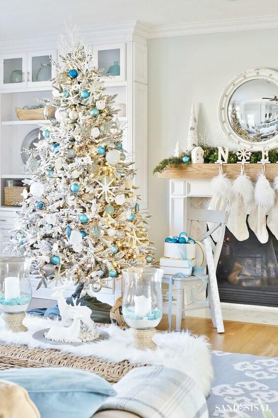 a beach Christmas space with a flocked Christmas tree, light blue and silver ornaments, starfish, an evergreen garland, blues and blue ornaments