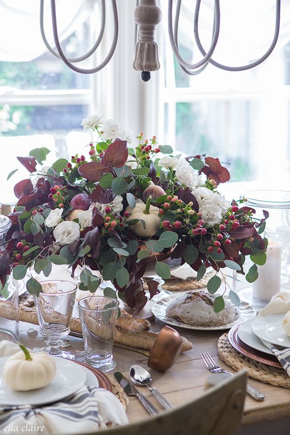 a beautiful and natural Thanksgiving centerpiece of usual and dark foliage, white pumpkins, berries and white blooms