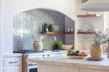 a beautiful white kitchen with planked cabinets, a blue Moroccan tile backsplash, stained stools and pendant lamps is cool