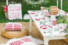 a bold Christmas picnic tablescape with a low table, eucalyptus, a gingerbread house and colorful plates plus bold pillows