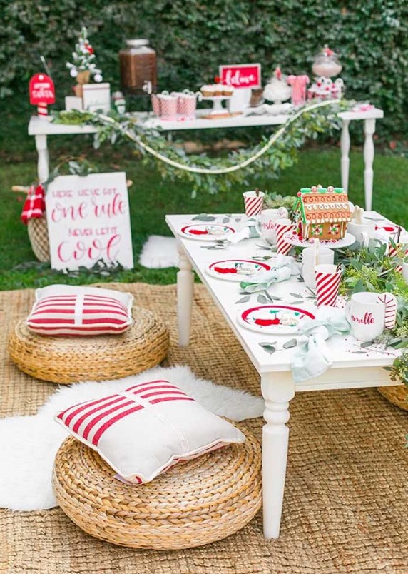 a bold Christmas picnic tablescape with a low table, eucalyptus, a gingerbread house and colorful plates plus bold pillows