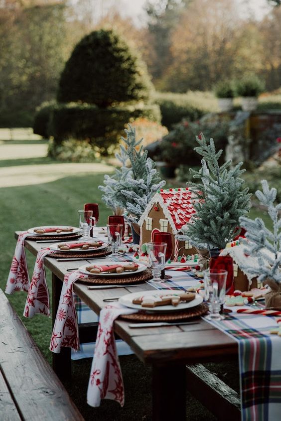 a bold and cool Christmas table setting with a plaid runner and printed napkins, tabletop Christmas trees, gingerbread houses and men