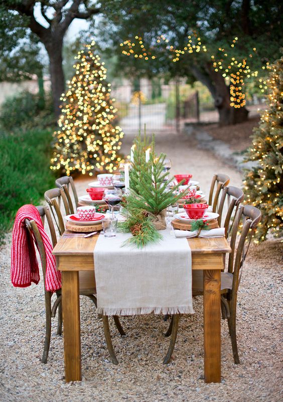 a bold and cool Christmas tablescape with a neutral runner, tree slice placemats, tabletop Christmas trees and red and white bowls