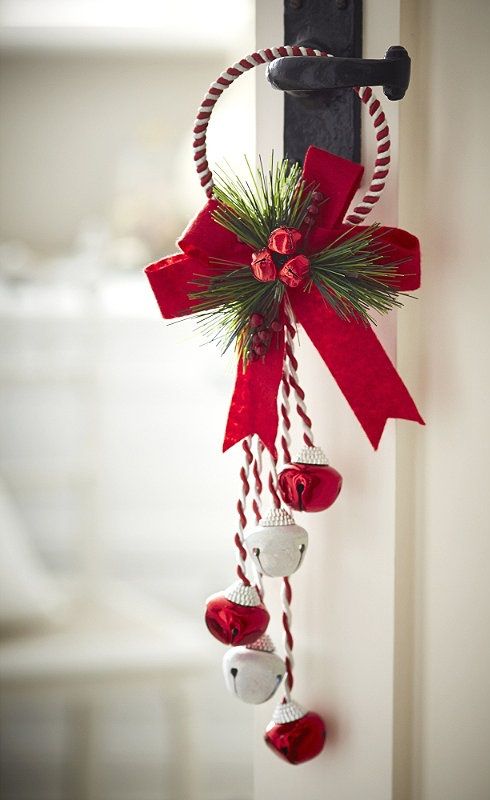 a bright Christmas door hanging of red and white bells, yarn, a red bow, fir twigs and berries is a cool decoration