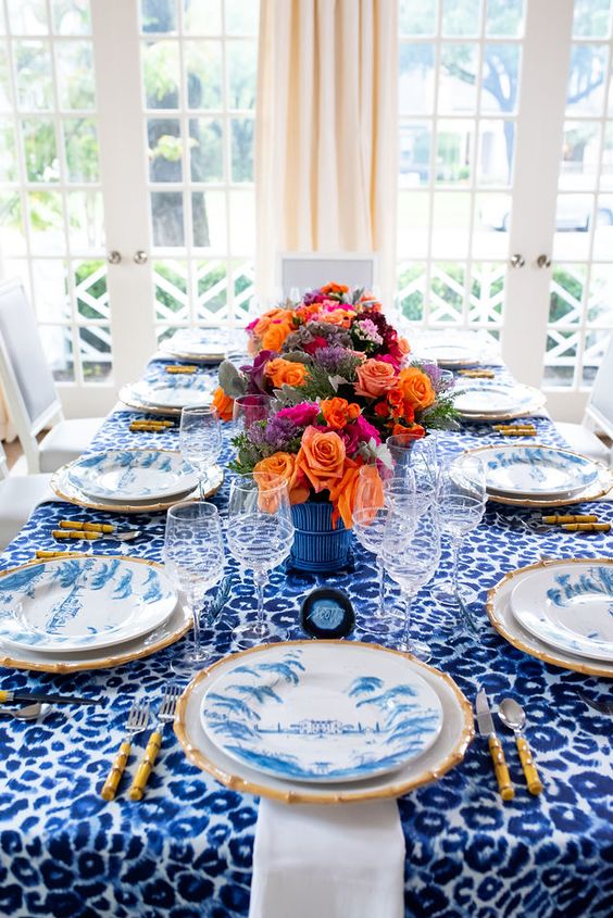a bright blue Thanksgiving tablescape with a leopard print tablecloth, blue and whiet porcelain and super bold blooms