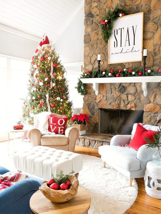 a bright holiday living room with a Christmas tree decorated with red and white ornaments, with a matching garland, red pillows and ornaments