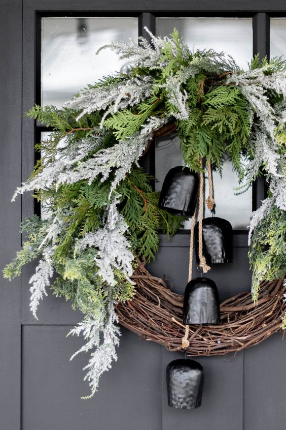 a catchy Christmas wreath of vine and flocked and usual evergreens and large black bells is a lovely and bold decoration