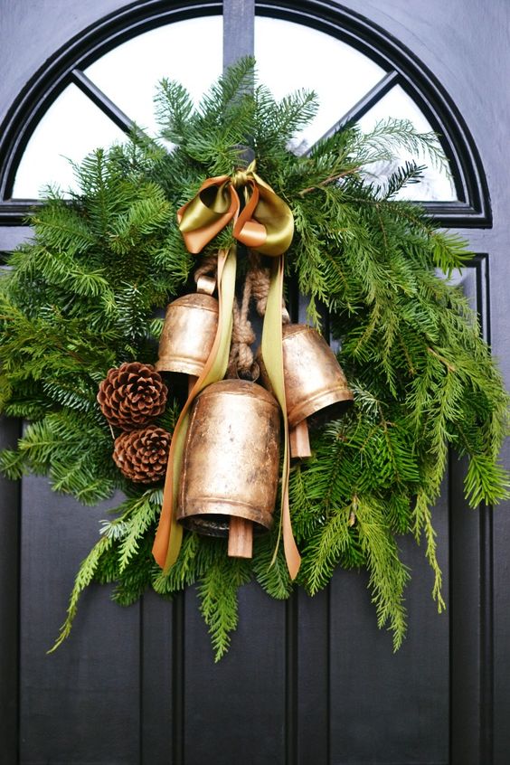 a chic Christmas wreath of fir branches with vintage bells, pinecones and rope is a pretty vintage holiday decor idea