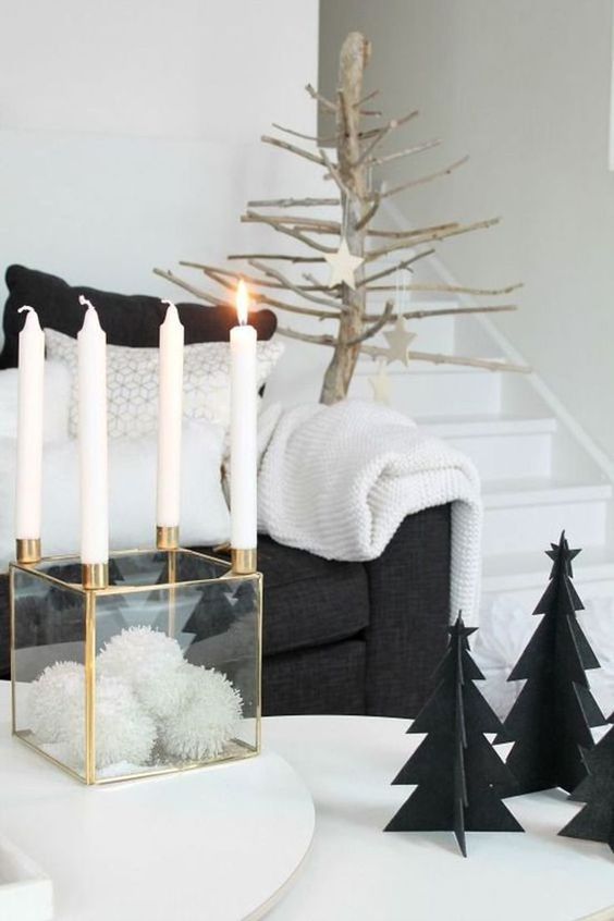 a clear box with white pompoms and candles on each corner, black cardboard Christmas trees and a tree with wooden stars