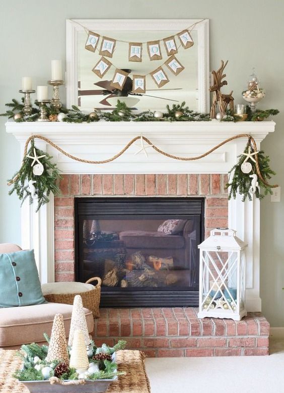 a coastal Christmas mantel with an evergreen, metallic ornaments, tope, seashells and sea stars is amazing