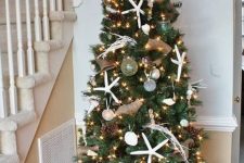a coastal Christmas tree with lights, pinecones, starfish, buoys, corals is a cool idea for a beach rustic Christmas tree