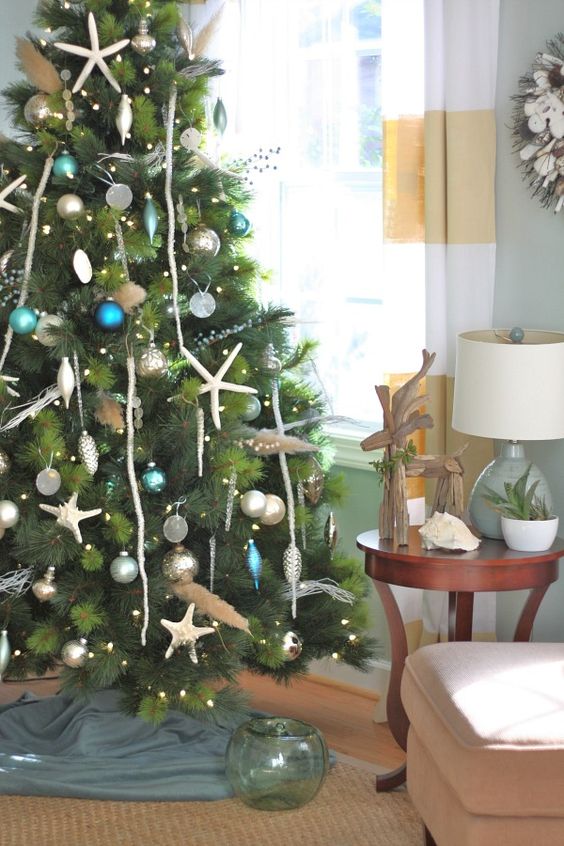 a coastal Christmas tree with lights, starfish, driftwood, blue, teal, green and silver ornaments is a gorgeous and refined idea