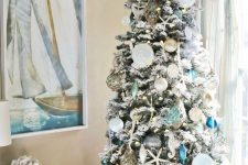 a coastal chic christas tree with navy, turquoise, mint and white Christmas ornaments, seashells, starfish and buoys