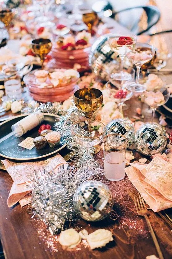 a colorful tablescape with disco balls, tinsel and gold cutlery for a sparkly New Year party
