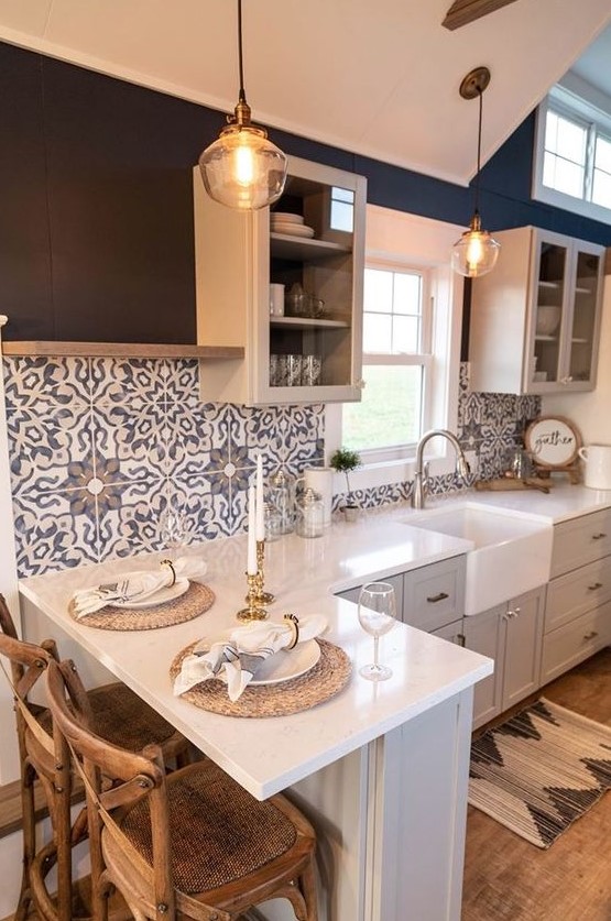 a contemporary grey kitchen with white countertops, blue Moroccan tiles on the backsplash and glass cabinets