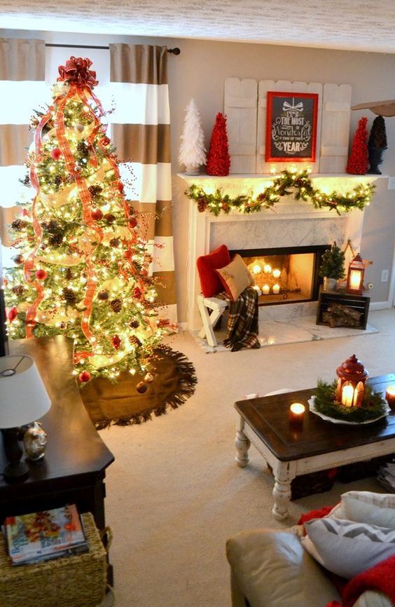 a cozy Christmas living room with a fir garland with lights, bright mini trees, a red lantern, a Christmas tree with lights, red ribbons, pinecones and red ornaments