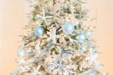 a dreamy coastal Christmas tree with light blue and mint buoy ornaments, sea horses, starfish, lights and a burlap bow on top