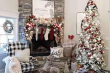 a farmhouse Christmas living room with a flocked Christmas tree with lights and white and red ornaments, a flocked garland with ornaments