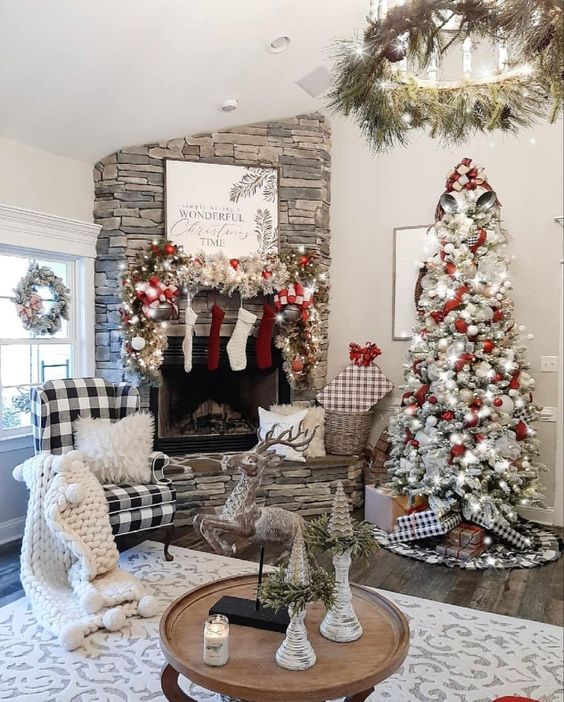 a farmhouse Christmas living room with a flocked Christmas tree with lights and white and red ornaments, a flocked garland with ornaments