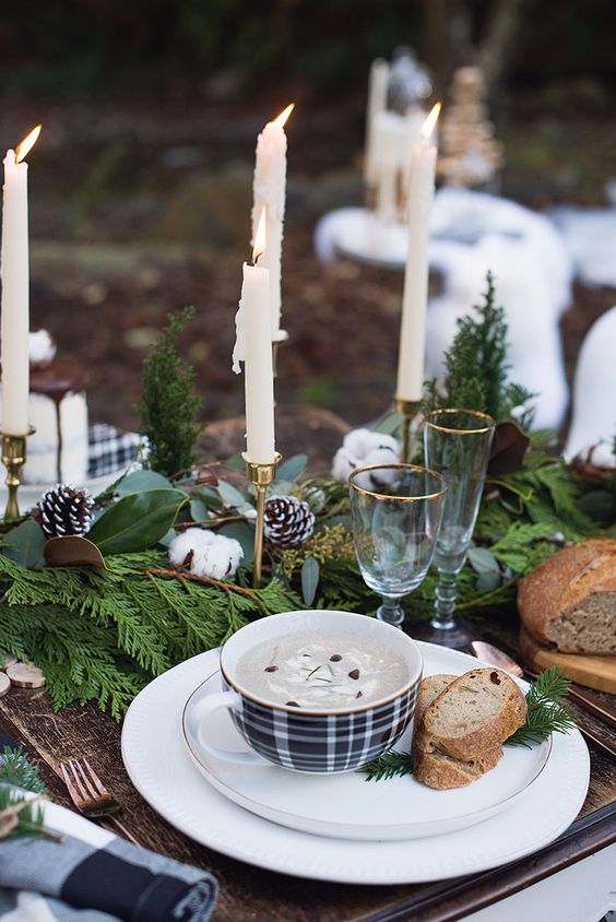 a farmhouse Christmas tablescape with an evergreen runner, cotton and snowy pinecones, tall and thin candles and white porcelain