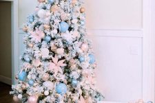 a flocked Christmas tree decorated with pastel pink and blush ornaments, pink fabric flowers and lights is gorgeous