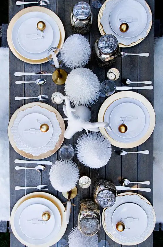 a fun holiday table setting with gold ornaments, pipe cleaner treesm a faux animal head and gold chargers