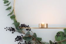 a gold wreath with privet berries and eucalyptus and some candleholders for a stylish minimalist space
