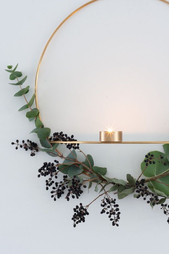 a gold wreath with privet berries and eucalyptus and some candleholders for a stylish minimalist space