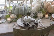 a lovely natural Thanksgiving tablescape with neutral heirloom pumpkins, tall candles, greenery and neutral linens