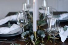a minimalist Christmas table with eucalyptus, white napkins and grey plates plus candles