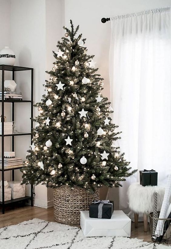 a minimalist Christmas tree in a basket decorated with lights and white oraments looks rustic, too