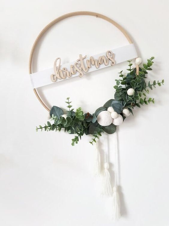 a minimalist Christmas wreath of an embroidery hoop, greenery, white pompoms and white tassels