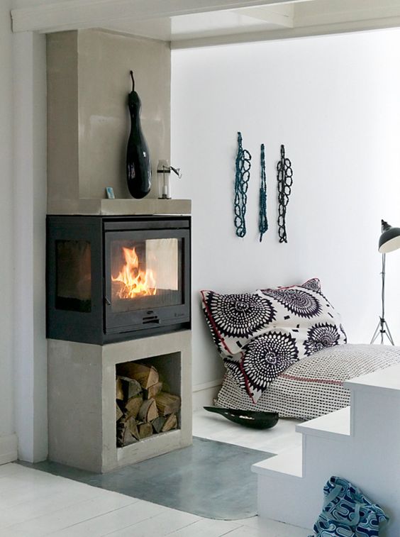 a modern fireplace set on a concrete niche with firewood for laconic and chic decor of the space